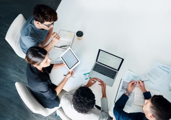 Overhead view of colleagues collaborating with laptops and notes at a table.